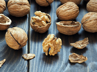 Walnuts in a wooden bowl on a dark background.