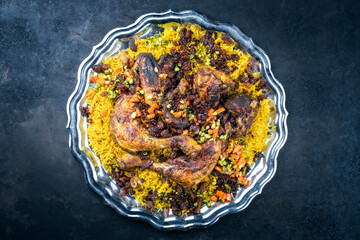 Traditional fried Arabic chicken majboos with chicken leg and jeweled rice served as top view in a rustic oriental tray