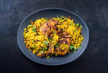 Modern style traditional fried Arabic chicken majboos with chicken leg and jeweled rice served as top view in a design plate with copy space
