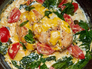 Chicken fillet with vegetables, herbs in white sauce is fried in a pan