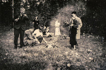 Germany - CIRCA 1930s: Adult friends relaxing at forest during picnic. Vintage Art deco era photo