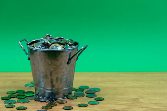 Many Coins Are In Silver Buckets On A Green Background. Money Overflow From Bucket. Coins Overflow From Silver Bucket