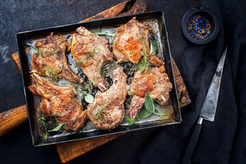 Traditional barbecue dry aged veal chops served as top view in a rustic tray on a black board