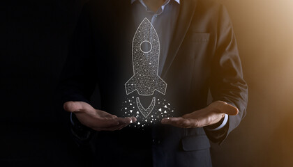 Startup business concept, Businessman holding icon transparent rocket is launching and soar flying out from screen with network connection on dark background.