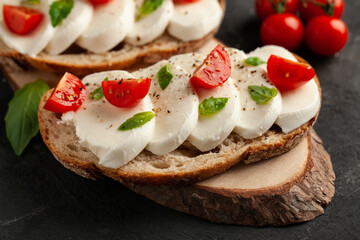 Ciabatta with cherry tomato, basil, mozzarella and spices. Bruschetta with cheese on concrete table. 