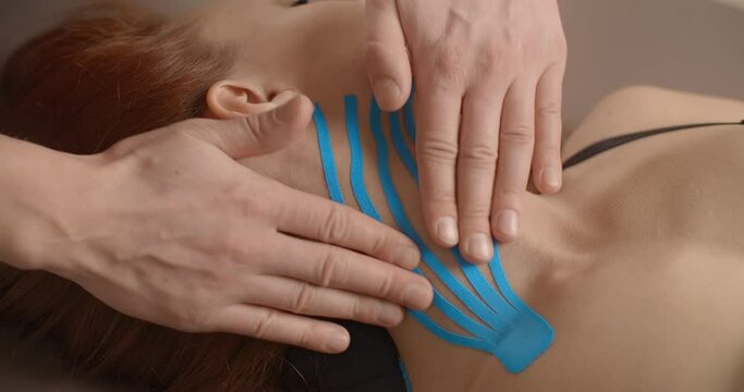 Kinesiologist sticks tapes to the neck of female patient, recovering after injury, kinesiotapes therapy, 4k 60p Prores HQ 10 bit