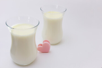 Two transparent glasses with white creamy Italian dessert Panna Cotta on a light background.