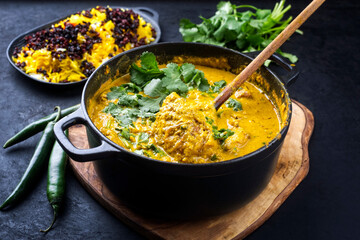 Traditional Indian chicken curry masala with saffron rice and berberis served as close-up in saucepan