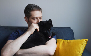 Man with his Schipperke dog at home.