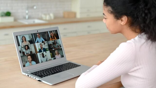 Mixed-race female student using application for distance video communication with classmates, webinar participants, studying online at home in pandemic, looking at laptop screen with people profiles