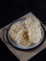 Ranginang or rangginang or rengginang is Indonesian traditional crispy rice or glutinous rice crackers, served in white plate against black background. Kind of deep fried food. 