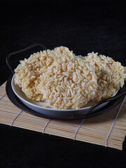 Ranginang or rangginang or rengginang is Indonesian traditional crispy rice or glutinous rice crackers, served in white plate against black background. Kind of deep fried food. 