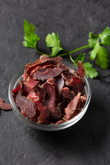 Bowl with jerky meat on a dark background