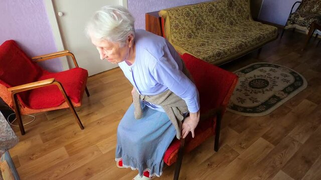 Elderly senior 75s woman with painful feelings massaging low back to reduce ache, backache discomfort. Diseases of older people, sciatic nerve injury concept
