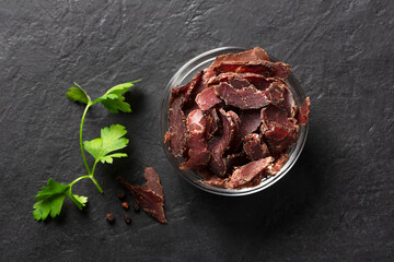 Bowl with jerky meat on a dark background