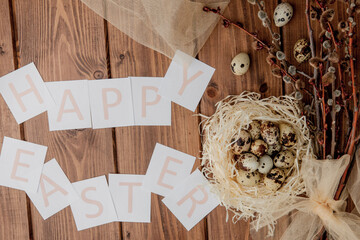 Flat lay composition of quail eggs and card with text Happy Easter on wooden table. Top view.