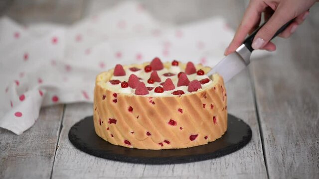 Cutting a raspberry mousse, French dessert. Beautiful mousse cake with fresh berries.