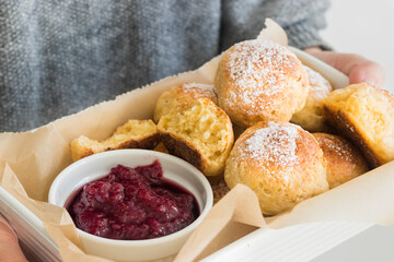 Freshly baked cottage cheese donuts with berry jam in a woman's hand