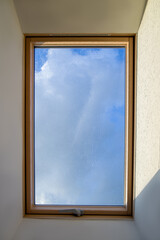 Window, attic, sky view through the roof window.