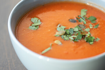 Bowl of red tomato cream soup on wooden table