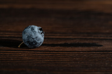 Blueberry in drops of water on wooden table. Copy space, close up