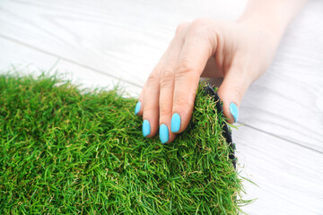 Tender female hand touching an artificial grass roll