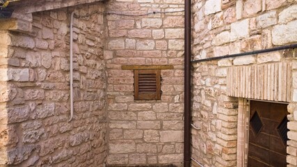 Fototapeta na wymiar Isolated tiny window with wooden shutters in a medieval brick building (Marche, Italy, Europe)