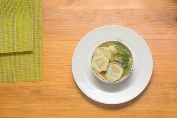 Plate of hot dumplings with sour cream and dill. Traditional Russian and Ukrainian cuisine