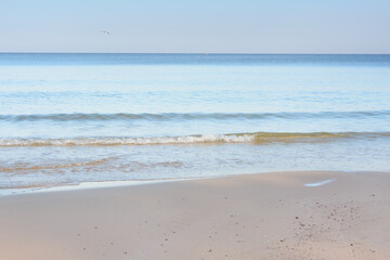 Obraz premium Evening beach on seashore. Soft sand and surf. Calm, summer mood. Beach resort concept