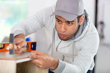 young cabinet maker using hammer and spirit-level