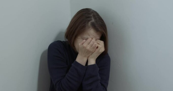 The concept of violence against a woman, in the family. A frightened girl sits in the corner of the room.