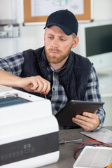 young male technician repairing digital photocopier