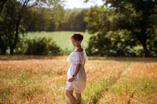 Eine h&uuml;bsche junge Frau, &uuml;ber 30 Jahre Alt, hat kurze Danke Haare und Schulter Ferienwei&szlig;es Kleid, dreht sich auf dem Feld, l&auml;chelt, tanz und sehr gut drauf!