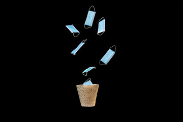 Several blue face masks falling into waste paper bin signifying the end of lockdown