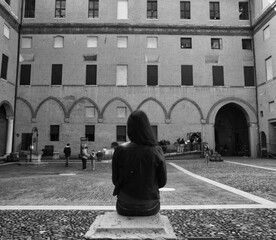 Young woman sit in the yard of the castle of Ferrara