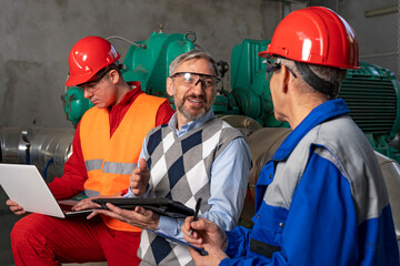 Smiling Manager Using Digital Tablet and Discussing About Production Process with Two Power Plant Workers