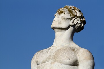 Athlete's bust seen from below at Stadio dei Marmi in Rome. Blue sky background