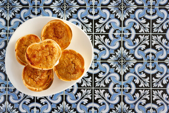 Traditional Portuguese pastry called Queijada de Sintra on portuguese tiles background. Top view with copy space