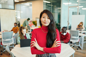 Young smiling businesswoman of Asian ethnicity crossing her arms by chest