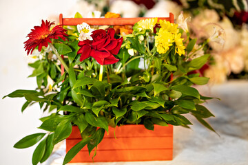 bouquet of roses and yellow flowers in a wooden basket.