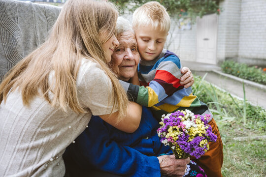 Family Groups, Multigenerational Households, Great-grandmother And Great-grandchildren. Candid Portrait Of Happy Grandmother With Grandchildren Outdoors