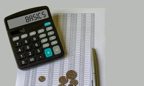 BASIC word on yellow sheet on table with pen, calculator and graph. Business and finance concept.