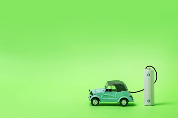 a small toy car and a battery on a green background. concept of electric vehicles, ecology and climate protection