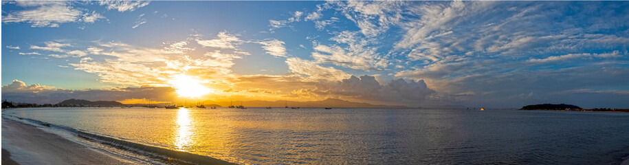 panoramic Sunset and orange clouds on a tropical beach with pirate boats in the background, located on the beach of Cachoeira do Bom Jesus, Canasvieras, Ponta das Canas, Florianópolis, Santa Catarina,