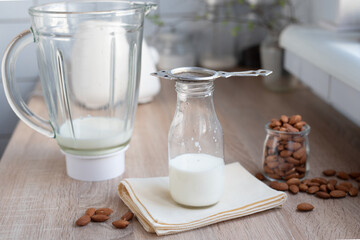 Almond milk in a bottle with a blender on the table in the kitchen, home cooking vegetable milk.