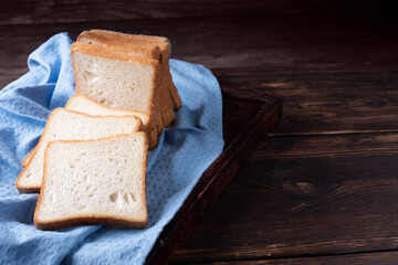 Sliced loaf of bread on a blue napkin on a wooden background.