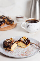 Traditional french dessert - eclairs with chocolate glaze. Eclair on a gray plate. Cut eclair. 