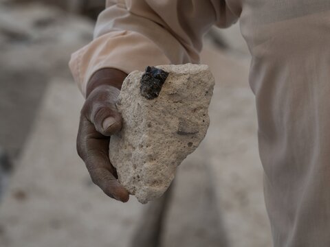 Quarry worker holding white sillar rhyolite volcanic rock stone brick block in dirty hand at Anashuayco Arequipa Peru