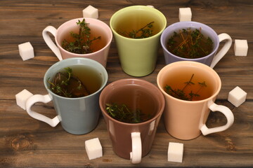Obraz na płótnie Canvas six multi-colored mugs of tea on a wooden table