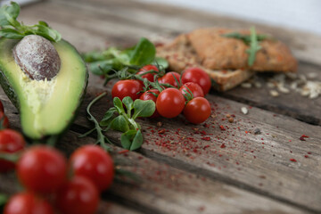 Rustic snack. Vegetables, cherry tomatoes, avocado, green sunflower seeds, and soft fresh rolls. Everything is laid out on boards in a rustic style
